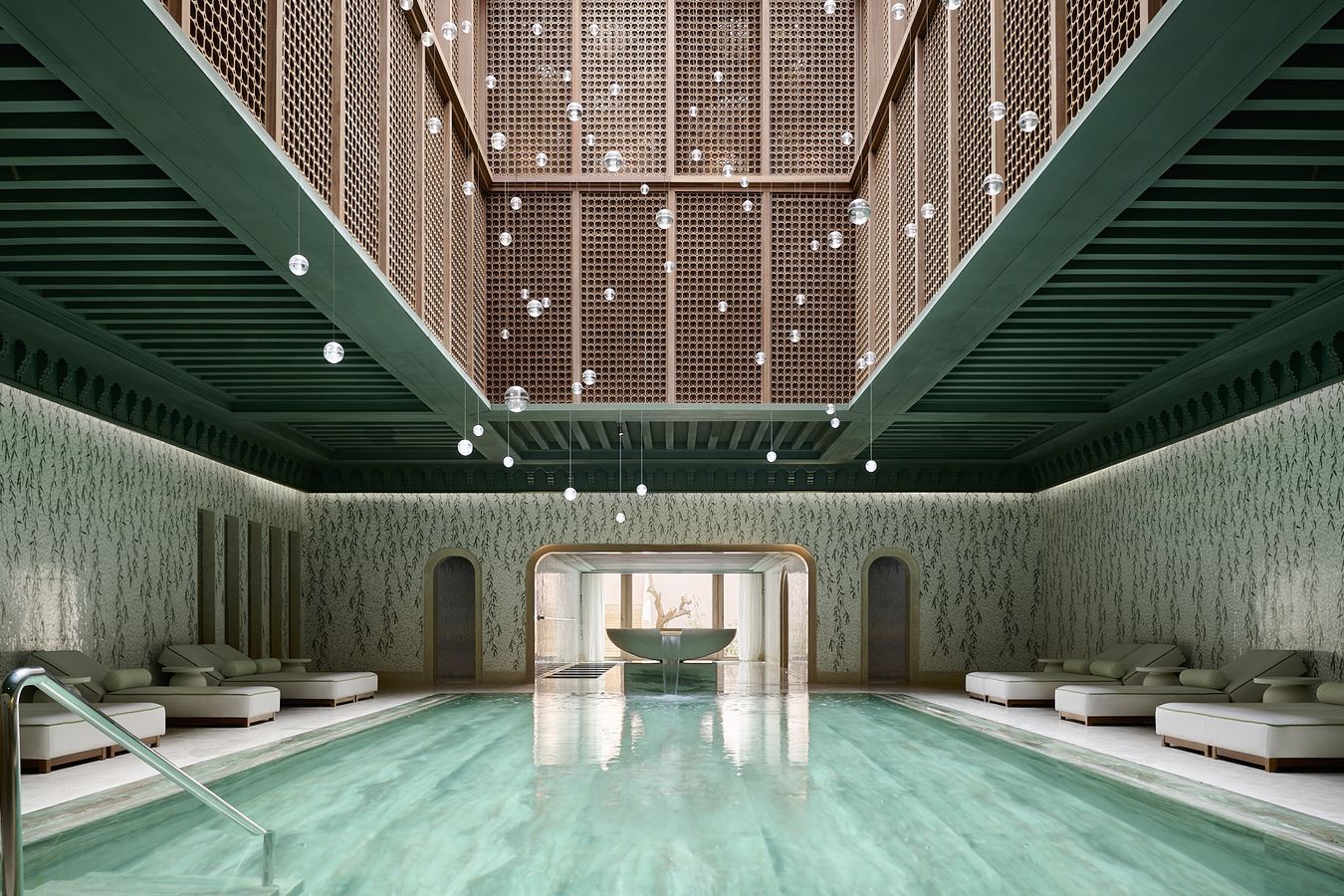 Binnenzwembad met groene mozaïekwanden en een hoog houten atrium met hangende glazen bollen in de spa van Royal Mansour Tamuda Bay